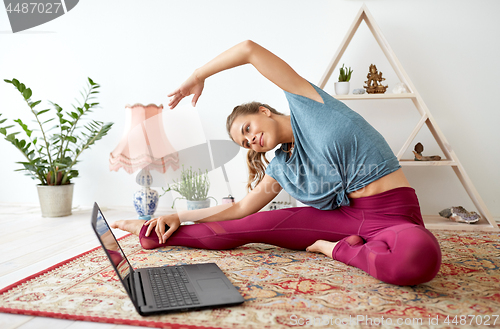 Image of woman with laptop exercising at yoga studio