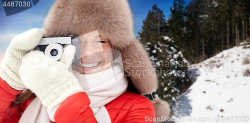 Image of happy woman with film camera over winter forest