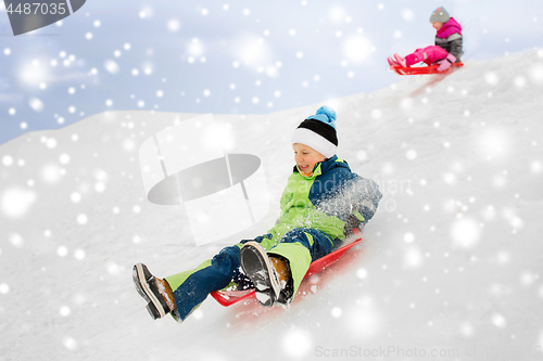 Image of happy kids sliding on sleds down hill in winter