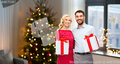 Image of happy couple with christmas gifts at home