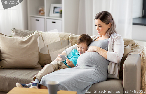 Image of pregnant mother and son with smartphone at home