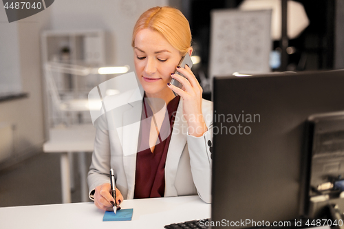 Image of businesswoman calling on sartphone at night office