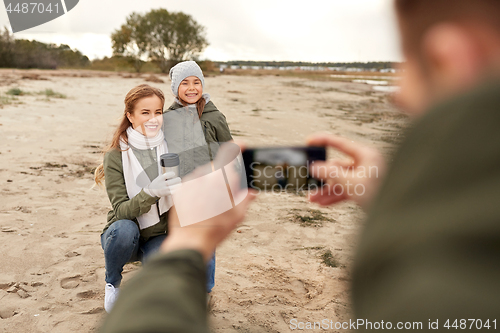 Image of family photographing by smartphone on autumn beach