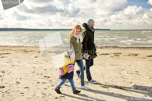 Image of happy family going to picnic on beach in autumn