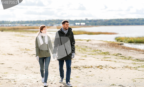 Image of couple walking along autumn beach