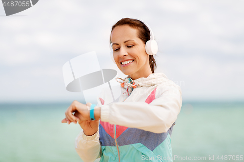 Image of woman with fitness tracker and headphones on beach