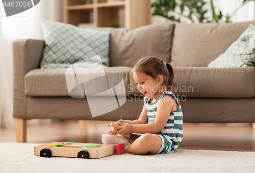 Image of happy baby girl playing with toy blocks at home