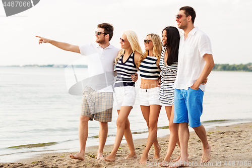 Image of friends in striped clothes walking along beach