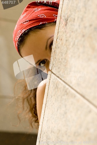 Image of woman looking behind a wal