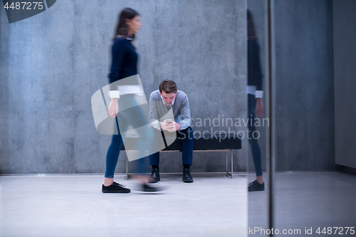 Image of businessman using mobile phone while sitting on the bench