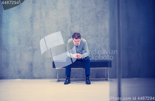 Image of businessman using smart phone while sitting on the bench