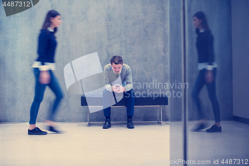 Image of businessman using mobile phone while sitting on the bench