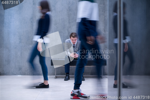 Image of businessman using mobile phone while sitting on the bench