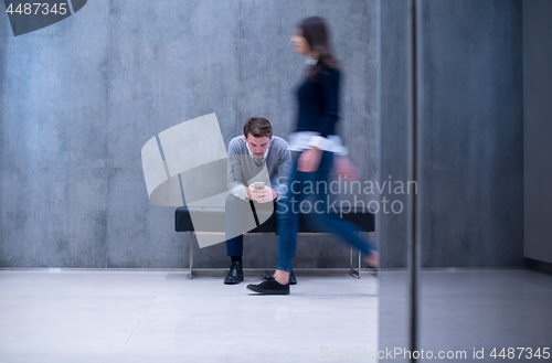 Image of businessman using mobile phone while sitting on the bench