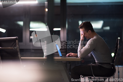 Image of man working on laptop in dark office