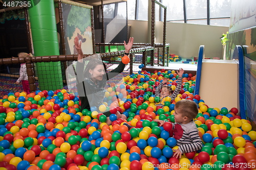 Image of Young mom with her kids in a children\'s playroom