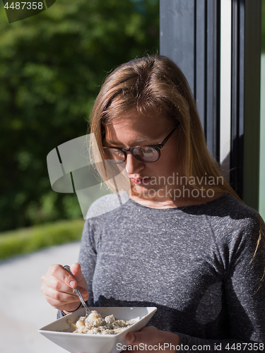 Image of woman eating breakfast in front of her luxury home villa