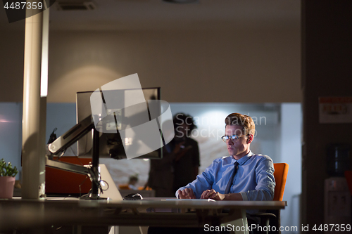 Image of man working on computer in dark office