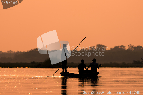 Image of Men in a boat on a river silhouette