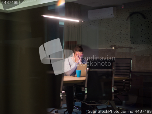 Image of man working on laptop in dark office