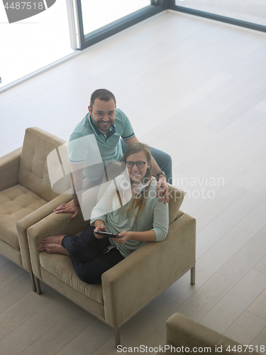 Image of couple relaxing at  home with tablet computers