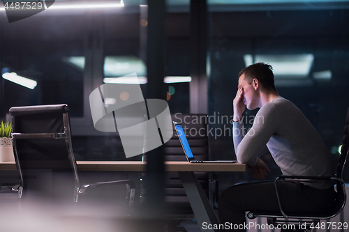 Image of man working on laptop in dark office