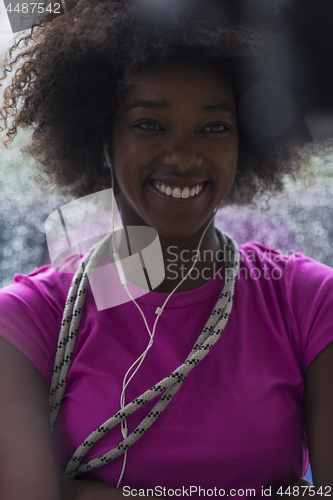 Image of portrait of young afro american woman in gym while listening mus