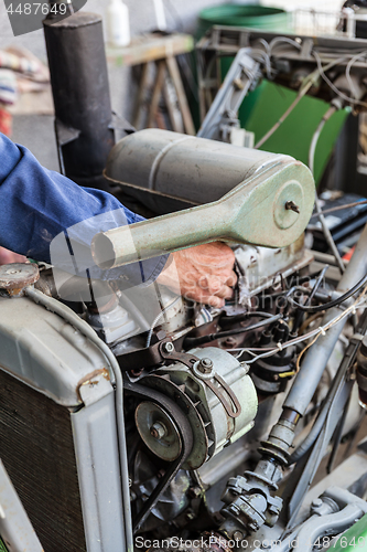 Image of Man repairing old dirty car engine