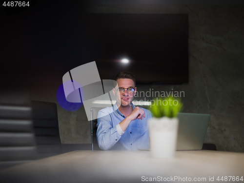 Image of man working on laptop in dark office