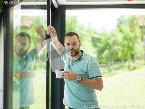 Image of young man drinking morning coffee by the window