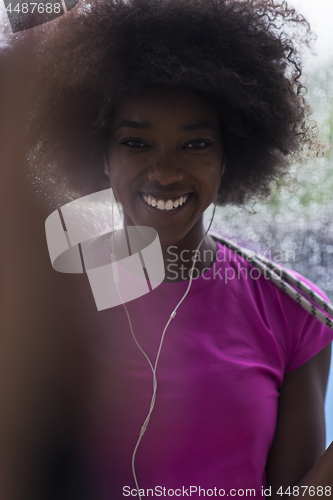 Image of portrait of young afro american woman in gym while listening mus