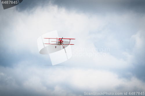 Image of Vintage red propeller plane flying on a blue sky