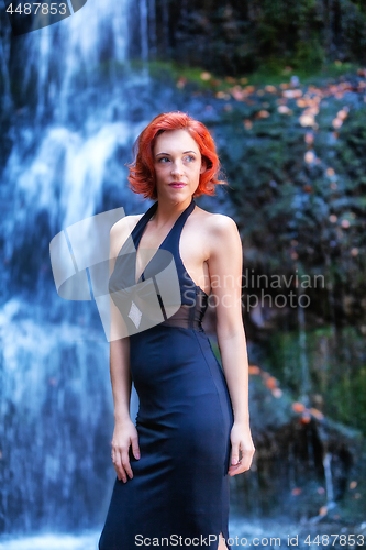 Image of Young woman stands in front of a waterfall