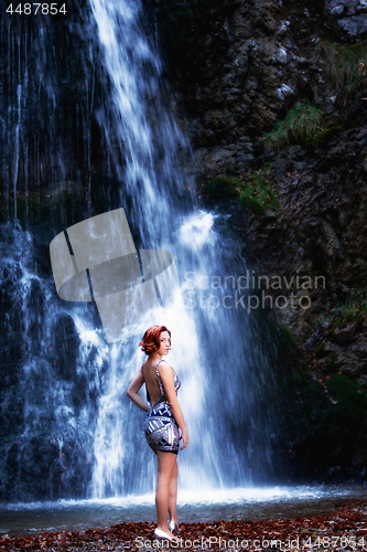 Image of Red-haired woman in front of a waterfall