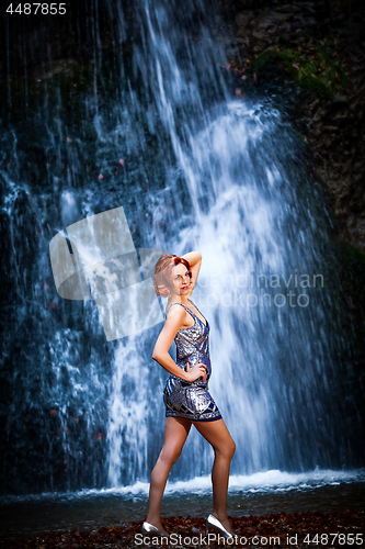 Image of Red-haired woman in front of a waterfall