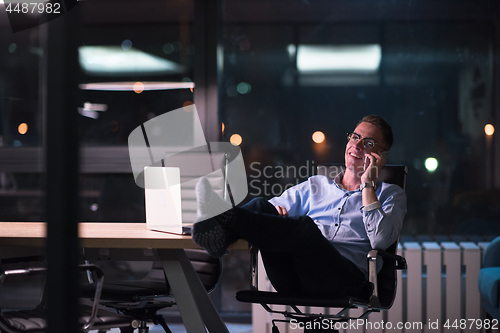 Image of businessman using mobile phone in dark office