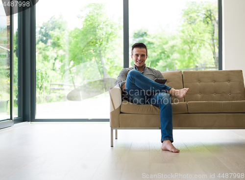 Image of man on sofa using tablet computer