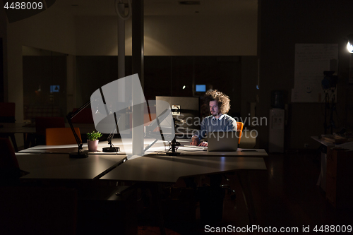 Image of man working on computer in dark office