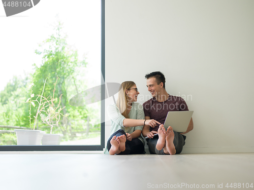 Image of couple using laptop on the floor at home