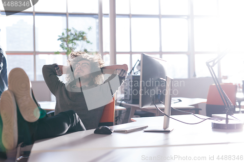 Image of businessman sitting with legs on desk