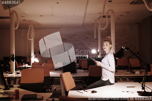 Image of woman working on digital tablet in night office