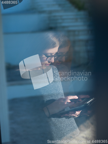 Image of Woman using tablet at home by the window