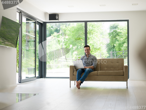 Image of Man using laptop in living room