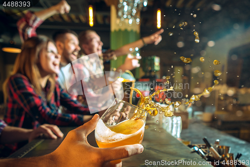 Image of sport, people, leisure, friendship and entertainment concept - happy football fans or male friends drinking beer and celebrating victory at bar or pub