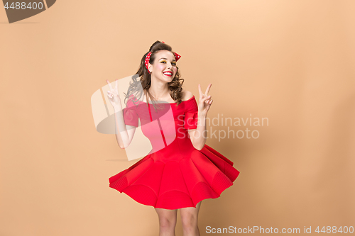 Image of Beautiful young woman with pinup make-up and hairstyle. Studio shot on pastel background