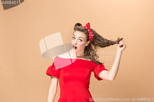 Image of Beautiful young woman with pinup make-up and hairstyle. Studio shot on pastel background