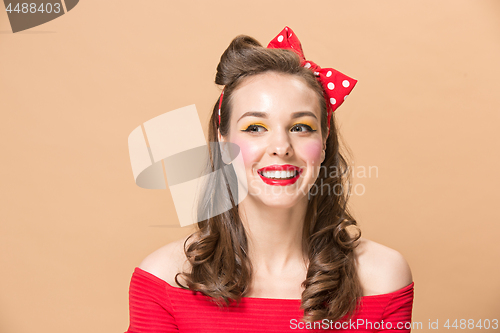 Image of Beautiful young woman with pinup make-up and hairstyle. Studio shot on pastel background