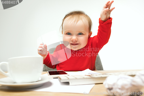 Image of Happy child baby girl toddler sitting with keyboard of computer isolated on a white background