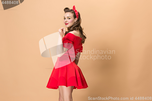 Image of Beautiful young woman with pinup make-up and hairstyle. Studio shot on pastel background