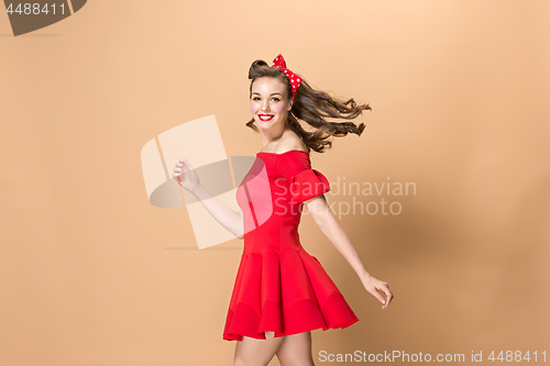 Image of Beautiful young woman with pinup make-up and hairstyle. Studio shot on pastel background